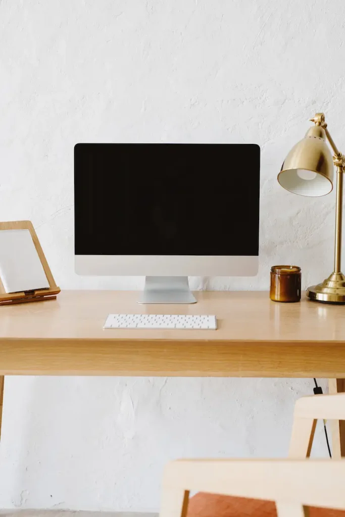 Bureau en bois avec ordinateur imac, lampe dorée et bougie,