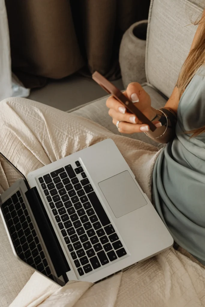 Femme qui passe un appel avec son smartphone et ordinateur posé sur ses genoux
