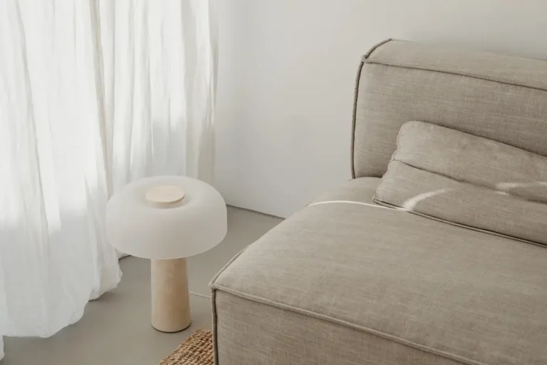 Salon minimaliste et épuré avec fauteuil, lampe et décoration douce dans des tons beiges