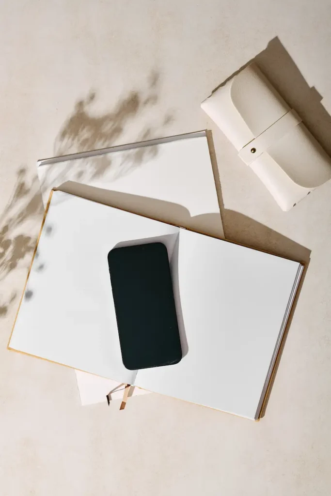 Smartphone posé sur un carnet dans une ambiance beige