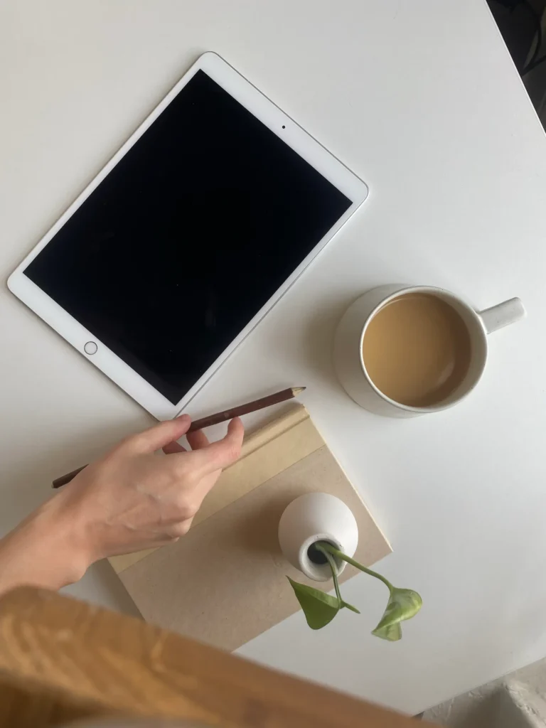 Tablette, carnet de note, café latte et crayon posé sur une table blanche